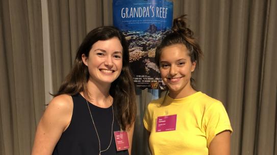 Vanina Harel and Sara Camnasio stand in front of a poster for their VR film "Grandpa's Reef"