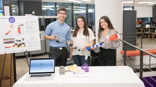 three students at their stall in the MakerSpace at the brooklyn showcase with 5 hand braces