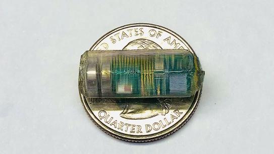 small device on top of a quarter to demonstrate scale