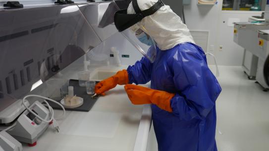 person dressed in cleanroom garb conducting research