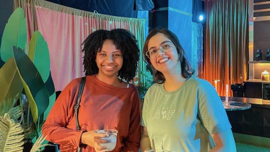 Two PhD students posing with props in front of a Squid Game-themed background.