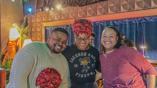 Three participants smiling together at the Squid Game event.