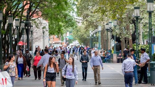 two students in NYU garb amongst a crowded outdoor commons