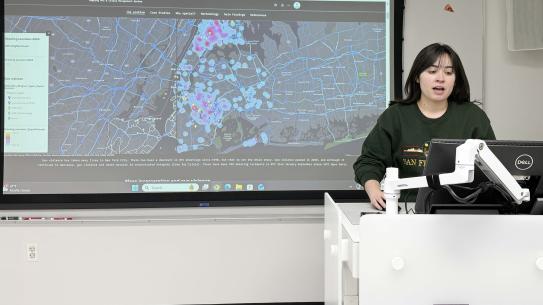 Gianna Campa presenting in front of a projection of a map of New York City.