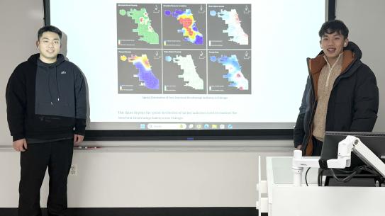Guanyu Chen and Shangyu Yang smiling in front of a projected map of Chicago