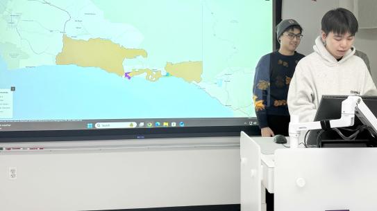 Haodong Ren, Leyan Chen, and Huayan Yu speaking in front of a map of Santa Barbara County.