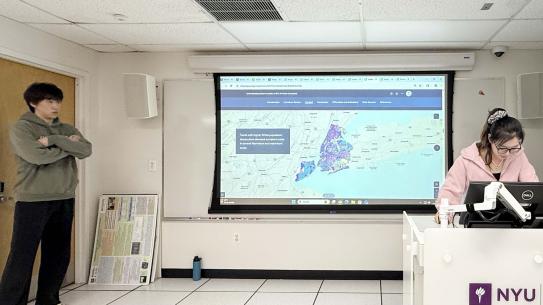 Jiatong Yao, Yixin Tang, and Mingda Wang speaking in front of a project map of NYC.