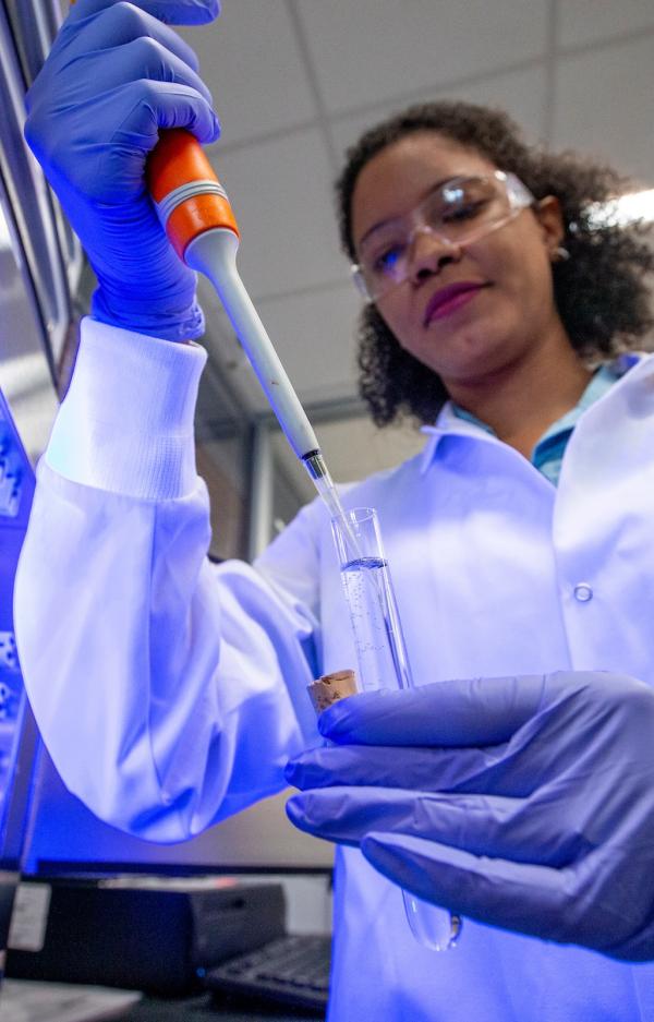 student in lab coat holding pipette