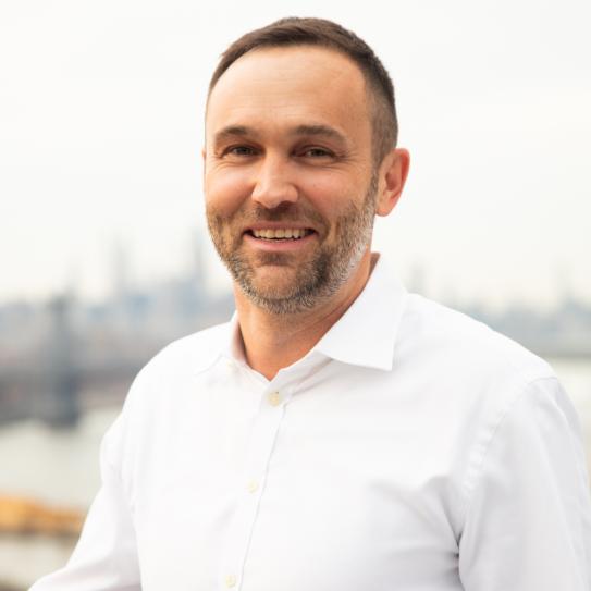 Man with cropped beard, short hair in a white shirt.