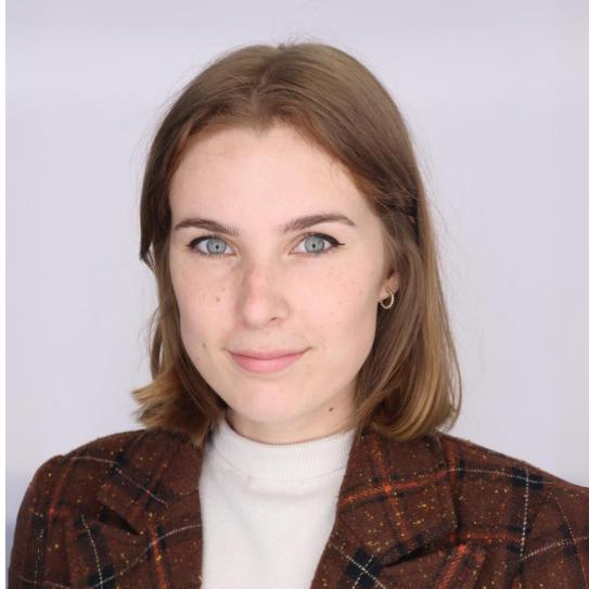 Picture of Faith Adams wearing a white turtleneck and brown blazer coat.