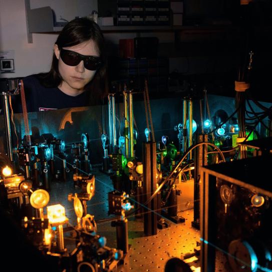 Amelia Klein wearing goggles behind a machine in a dark room.