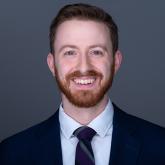 Headshot of man smiling in front of gray background