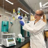 Sasha Visek in a lab, smiling while holding a test tube