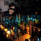 Amelia Klein wearing goggles behind a machine in a dark room.