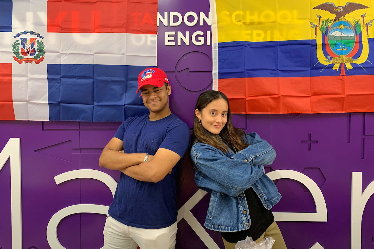 2 latinx students posing in front of flags