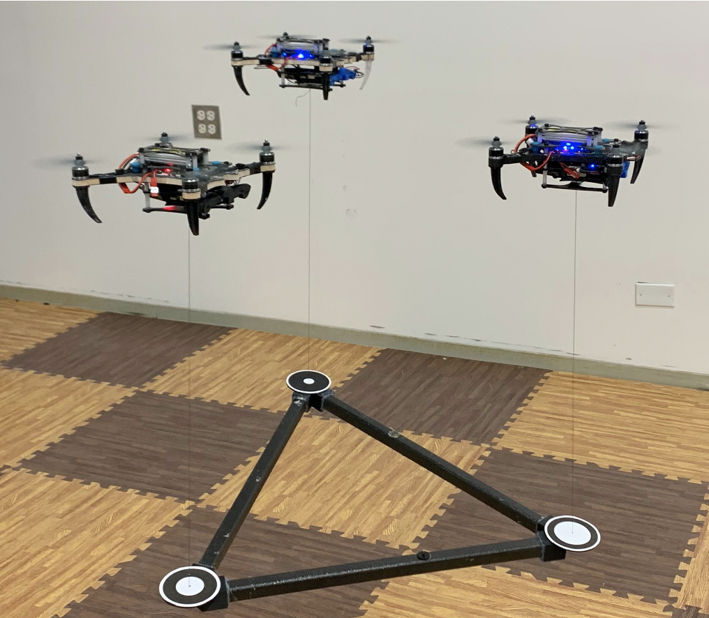 Three drones carrying a triangular object.