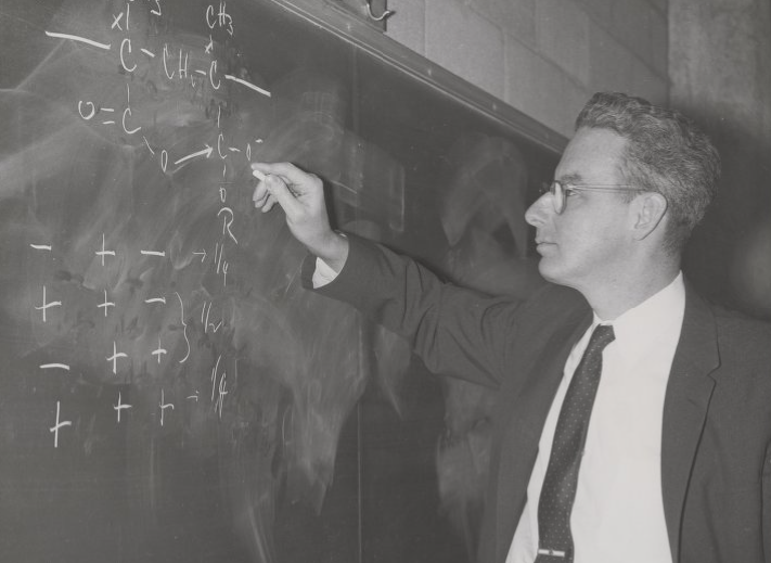 A young Herbert Morawetz writing an equation on a chalk board
