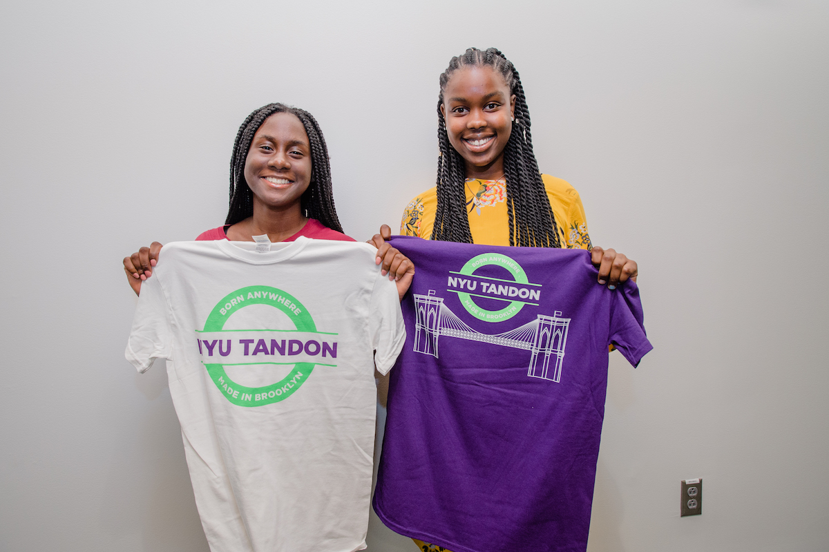 2 black female students holding Tandon shirts