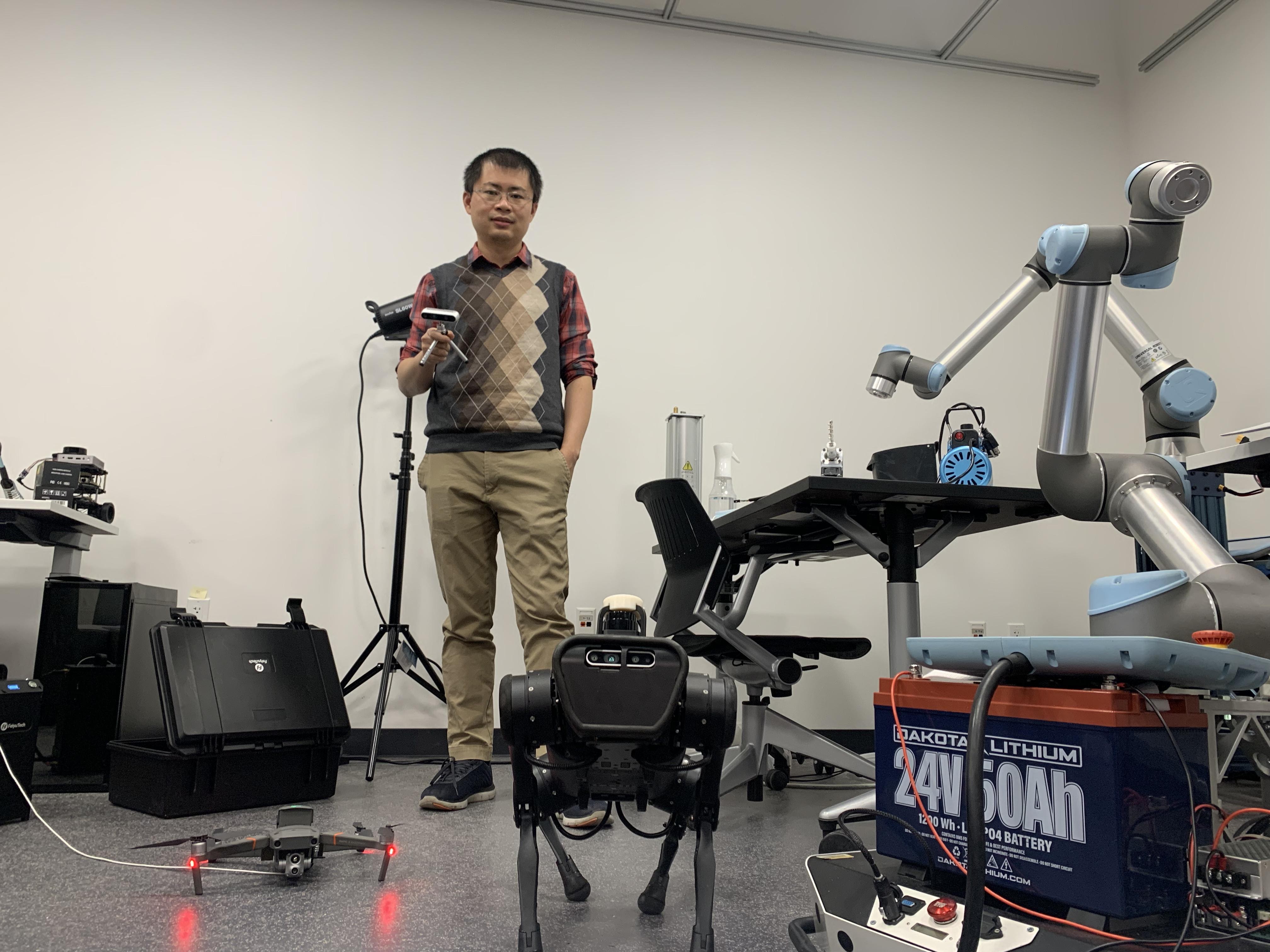 Chen Feng in robotics lab holding controler