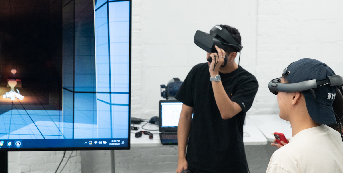 2 students wearing vr headsets looking at large screen